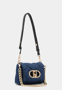 Geantă din denim tip crossbody cu un design matlasat, accesorii aurii și o curea din lanț. Prezintă un logo proeminent pe închizătoarea cu clapetă.