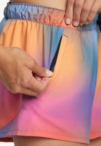 Pantalones cortos atléticos ligeros y coloridos con un degradado de naranja a azul, que cuentan con un bolsillo lateral con cremallera y una cinturilla elástica.