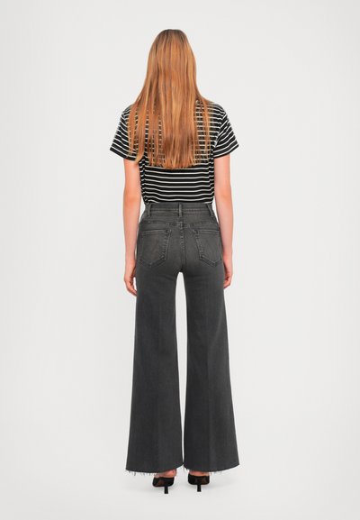 Black and white striped t-shirt with short sleeves, paired with high-waisted, wide-leg, gray denim jeans and black heeled shoes.