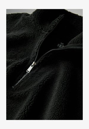 Black fleece pullover with a high collar and a silver zipper. The fabric has a soft, textured surface. Interior label is visible.