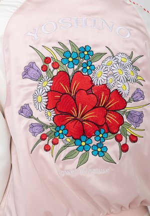 Rückseite einer rosa Satinjacke mit gesticktem roten Hibiskus, blauen und weißen Gänseblümchen, lila Blumen, roten Beeren und dem Schriftzug "YOSHINO" über dem Blumenmuster.