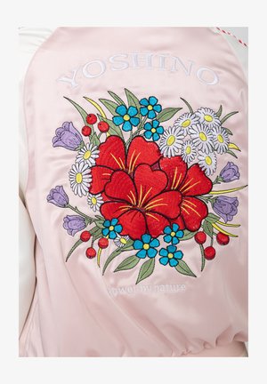 Rückseite einer rosa Satinjacke mit gesticktem roten Hibiskus, blauen und weißen Gänseblümchen, lila Blumen, roten Beeren und dem Schriftzug "YOSHINO" über dem Blumenmuster.
