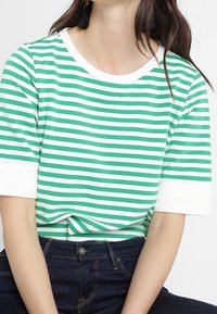 Grön- och vitrandig t-shirt med rund halsringning och korta ärmar, med en avslappnad passform och mjuk bomullstextur.