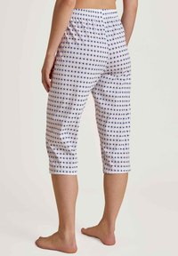 Witte capri-broek met een blauw en rood geometrisch patroon, elastische tailleband en een cropped fit. Glad materiaal met een lichte textuur.