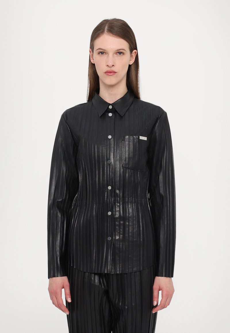 Schwarzes, plissiertes Hemd aus glänzendem Material mit Kragen, durchgehendem Knopfverschluss und einer Brusttasche. Die Textur erscheint glatt mit vertikalen Linien.