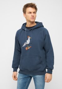Marineblauwe hoodie van zacht materiaal, met een grafisch ontwerp van een meeuw met een beanie op een drinkfles. Voorzak met kangoeroe-pocket.