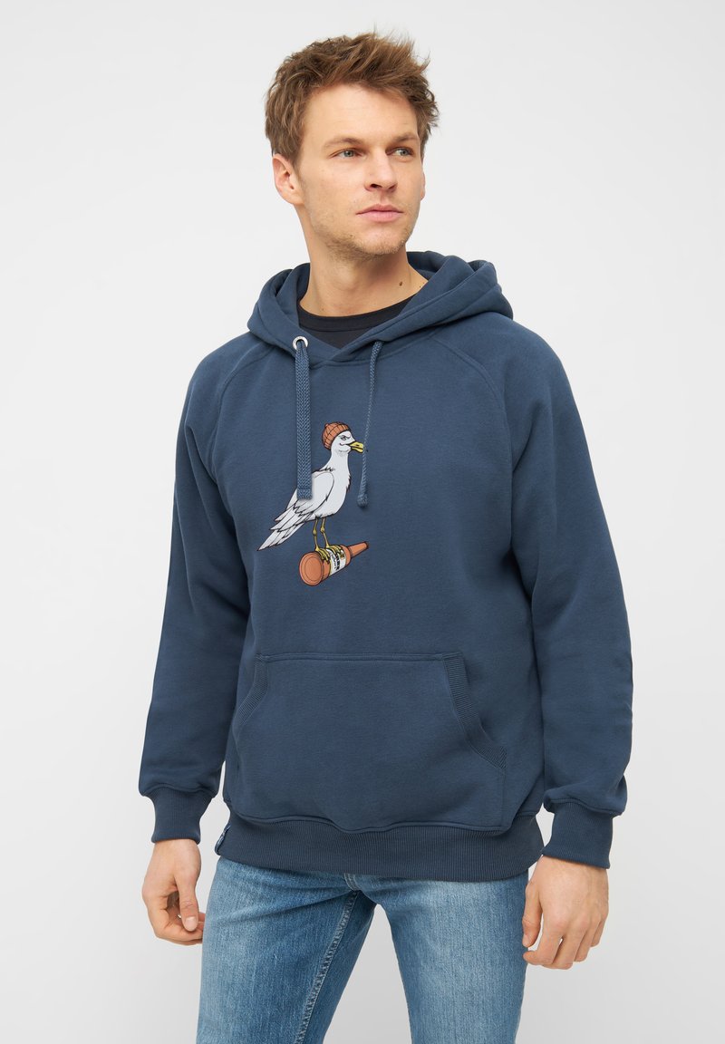 Marineblauwe hoodie van zacht materiaal, met een grafisch ontwerp van een meeuw met een beanie op een drinkfles. Voorzak met kangoeroe-pocket.