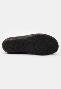 Black rubber shoe sole with a textured surface featuring a pattern of irregular, jagged shapes for traction and durability.