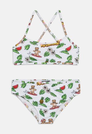 Valge kaheosaline ujumistrikoo ristseotistega seljal, millel on surfitavade nukkude kujutised, rohelised lehed, ananassid, hibiskuseõied ja arbuusiviilud.