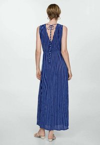 Robe maxi à rayures bleu marine avec un dos en V, détail à nouer, sans manches et taille cintrée. Tissu doux avec une silhouette fluide.