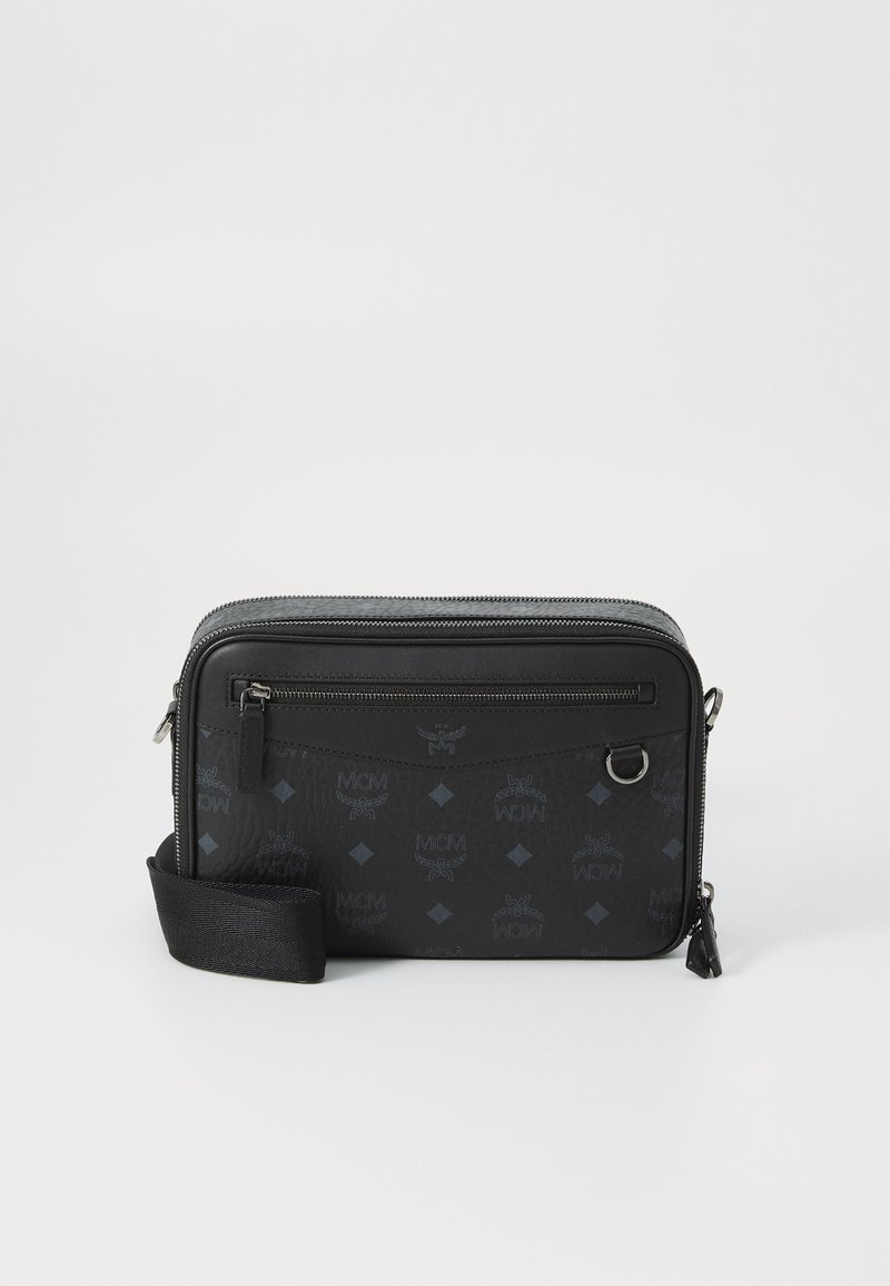 Melna plecu soma ar gludu tekstūru, ar rāvējslēdzēja aizdari, priekšējo kabatu un reljefa logotipa rakstu. Iekļauta regulējama siksna.