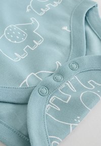 Hele sinine puuvillane kehakate valge elevandimustriga, ümmarguse kaelusega ja all olevate nööpidega, et muuta vahetus lihtsaks.