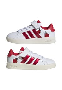 Baskets blanches avec accents rouges et bandes en cuir verni. Comprend des graphismes de coccinelle, une bride à scratch et une semelle en caoutchouc.