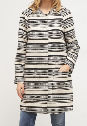 Lange, crèmekleurige jas met zwarte geometrische patronen, voorzakken en een knoopsluiting. Rechte snit met een capuchon en lange mouwen.
