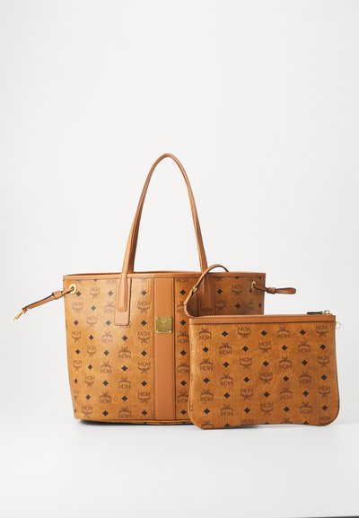 Tan leather tote bag with MCM logo pattern and matching zippered pouch, both featuring gold-tone hardware and dual top handles.