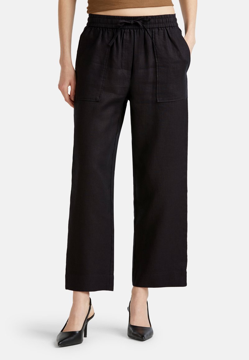 Pantaloni ampi in lino nero con vita elastica, dettaglio con coulisse e due tasche frontali. Texture liscia e vestibilità rilassata.