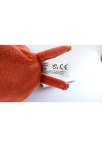 Plush toy with soft, orange fabric, featuring rounded body and prominent bunny ears. Tag displays UKCA and CE certification information.