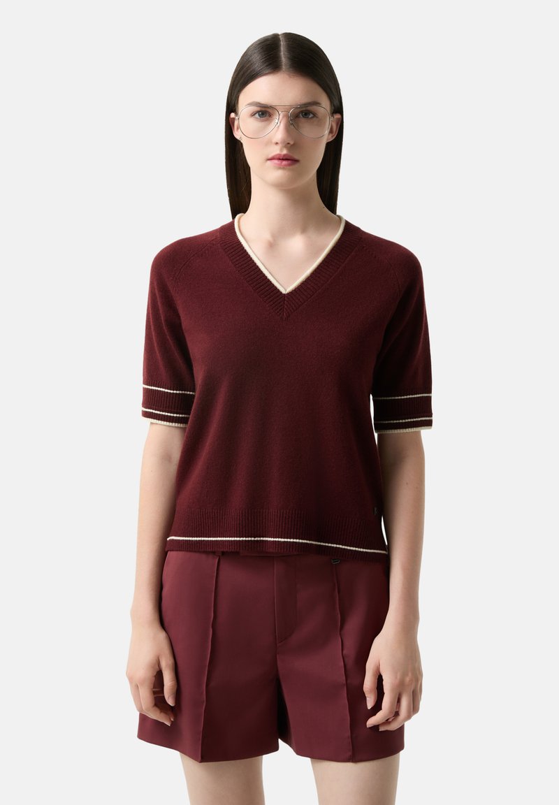 Bordový svetr s krátkým rukávem a výstřihem do V, s kontrastním krémovým lemem na rukávech a spodním lemu, spárovaný s odpovídajícími šortkami. Měkká pletená textura.