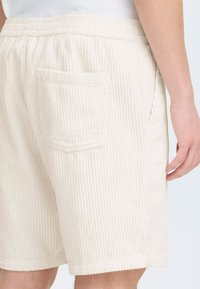 Kremfargede kordfløyelsshorts med ribbet tekstur, med en baklomme og en myk elastisk midjebånd.