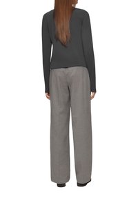 Zwarte long-sleeve top gecombineerd met grijze, hooggesneden, losse broek, met een gestructureerde stof en een strakke, minimalistische uitstraling.