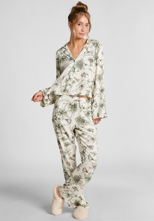 Bloemen pyjama set met een langmouwen top en broek met elastische taille in crème met groene botanische patronen. Zachte, lichte stof en een comfortabele pasvorm.
