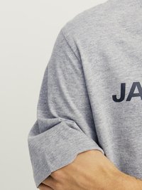 Grå t-skjorte med rund hals laget av myk bomullsmikstur; har korte, rullede ermer og et mørkt trykk av ordet "JACK" over brystet.