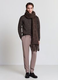 Brauner gestrickter Pullover, hellbeige Hose, dunkelbrauner Schal mit Fransen und glänzende schwarze Stiefel. Einfaches und modernes Outfit-Design.