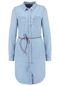 Robe-chemise en denim bleu clair à manches longues avec boutons sur le devant, deux poches poitrine, col pointu et une fine ceinture marron nouée à la taille.