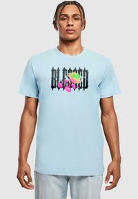 Himmelblaues Baumwoll-T-Shirt mit einem grafischen Design und dem Text "BLESS" in Schwarz sowie einem bunten Rosenmotiv, kurzen Ärmeln und einer lockeren Passform.