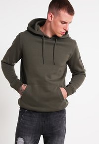 Groene hoodie met een voorste kenguruzak en zijzak met rits. Getailleerd ontwerp, katoenmix stof en ribbelmanchetten.