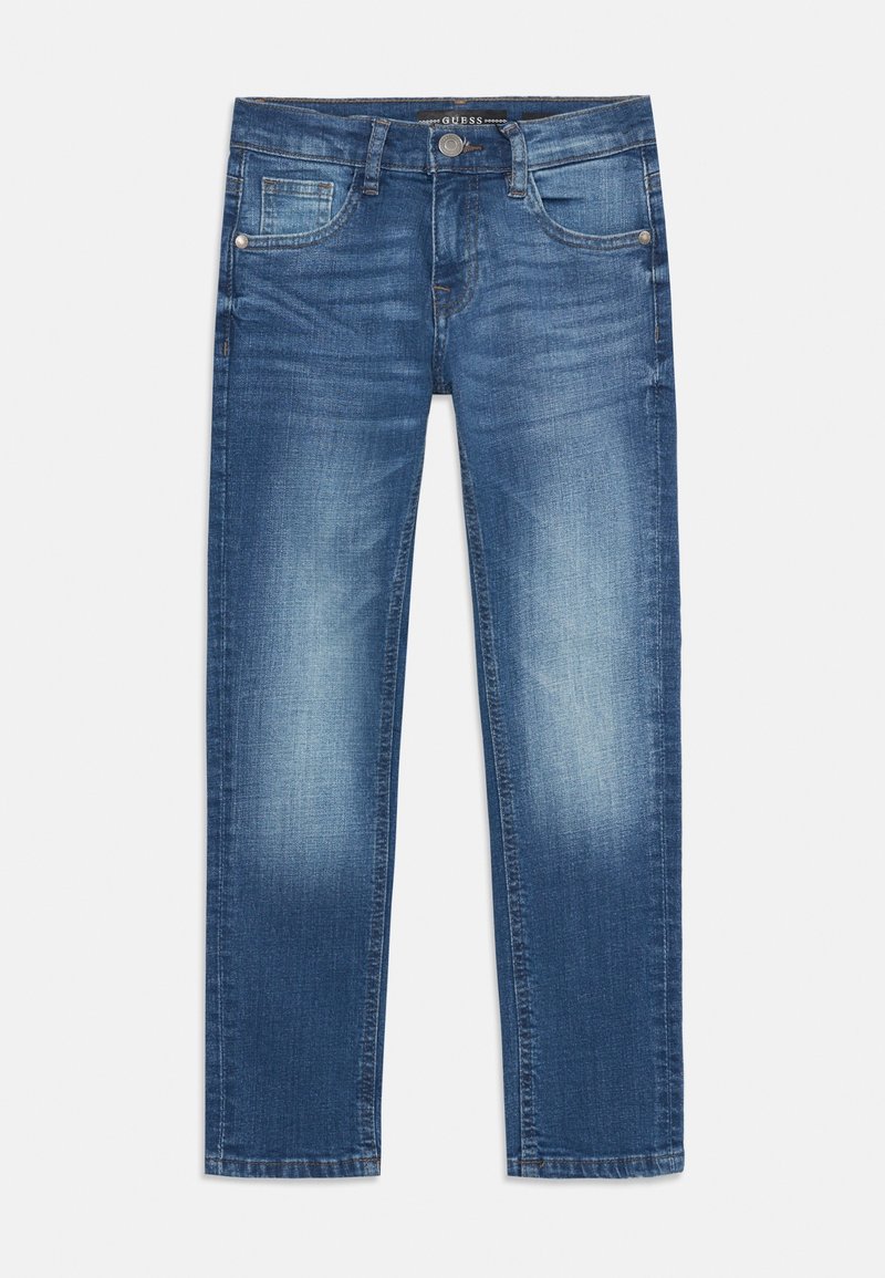 Jean slim délavé bleu avec poches avant, passants de ceinture et fermeture à bouton de la marque Guess sur un fond uni.