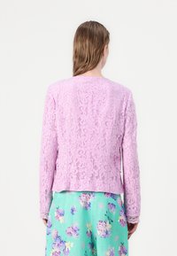 Spitzenjacke in helllila mit kunstvollen Blumenmustern. Verfügt über lange Ärmel, einen runden Halsausschnitt und einen leicht verkürzten Schnitt.