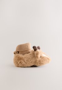 Zapatillas peludas de color beige con un puño de tejido acanalado. El diseño incluye orejas y cuernos, textura suave y una puntera redonda con una nariz bordada.