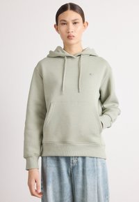 Mintgrønn hettegenser laget av myk stoff, med en frontlomme, snorer og en liten brodert logo på brystet.