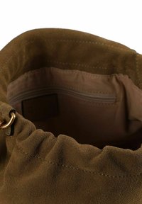 Borsa in suede marrone con bordo superiore arricciato, caratterizzata da una leggera lucentezza. La fodera interna ha una tasca con zip e una texture liscia.