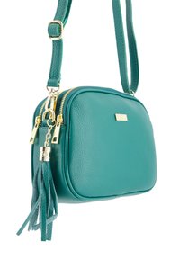 Turkis læder crossbody taske med guldfarvet hardware, lynlås og en dekorativ kvast. Kompakt rektangulær form, tekstureret overflade.