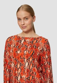 Rode slangenprint top met een brede halslijn en lange mouwen. Bevat een gestructureerd patroon in tinten van oranje, zwart en crème.