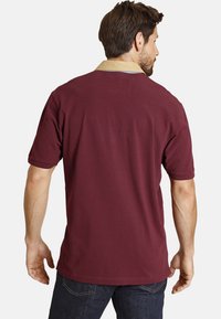 Burgundy short-sleeve polo shirt with a cream collar, made from cotton, featuring a relaxed fit and a smooth texture.