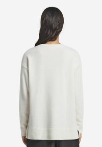 Cremefarbenes Sweatshirt aus weichem Material, mit lockerer Passform, geripptem Saum und langen Ärmeln. Minimalistisches Design, ohne Drucke oder Muster.