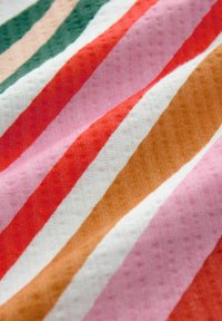 Tissu rayé multicolore comprenant de larges rayures texturées en rouge, rose, blanc, vert et marron. Surface lisse avec des motifs subtils.