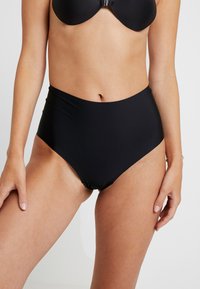 Bas de bikini noir taille haute fabriqué dans un tissu lisse, avec une coupe classique et des lignes épurées, avec des détails de couture minimaux.