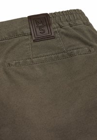 Groene stoffen shorts met een textuurweefsel, versterkte stiksels en een bruine leren patch met een reliëflogo. Elastische tailleband voor comfort.