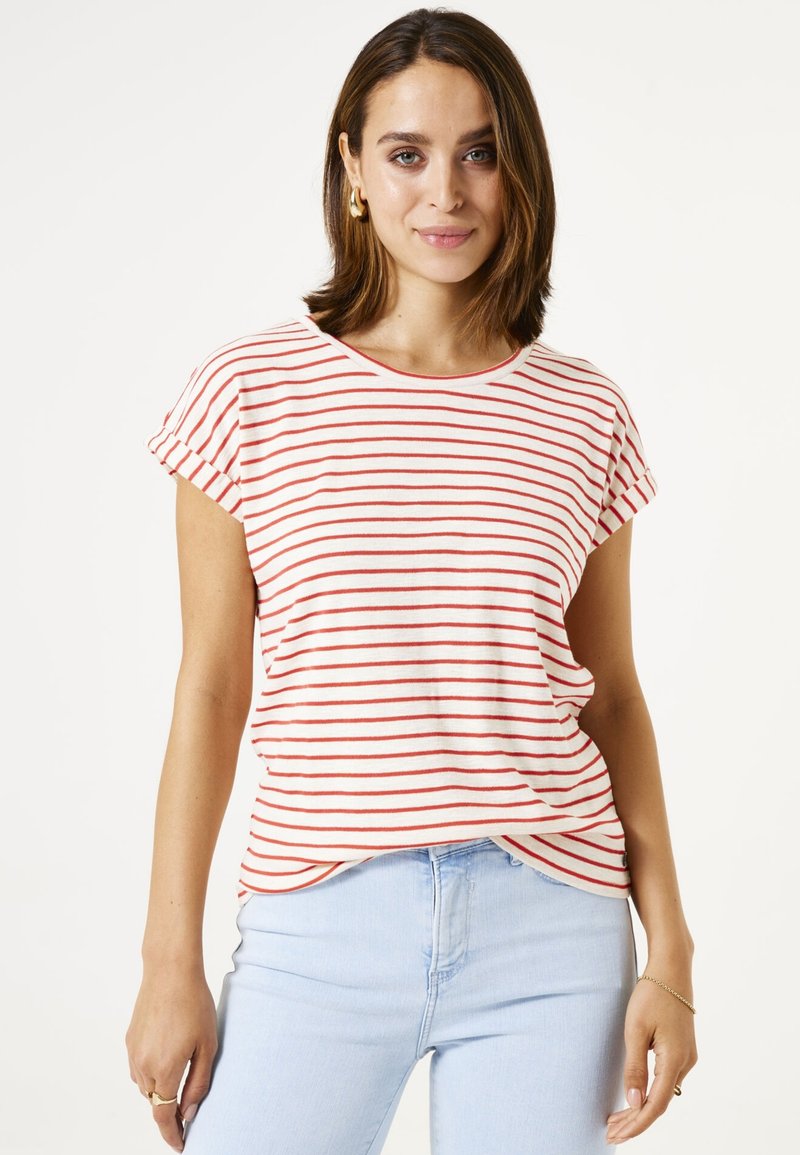 Gestreiftes T-Shirt in Creme und Rot, kurze Ärmel mit umgeschlagenem Saum, runder Halsausschnitt, lockere Passform, kombiniert mit hellblauen Jeans.