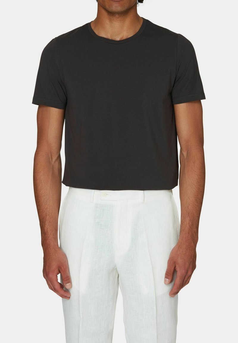 T-shirt in cotone nero con scollatura tonda classica, maniche corte e vestibilità comoda, abbinata a pantaloni in lino bianchi plissettati.