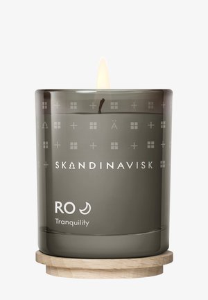 Duftlys i et frostet gråt glas med indgraverede mønstre. Træbase understøtter glasset. Mærkatet viser "Skandinavisk" og "RO Tranquility."