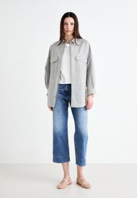 Camisa de botones a rayas en gris claro con dos bolsillos en el pecho, combinada con vaqueros azul claro de media longitud y flats tejidos rosas.