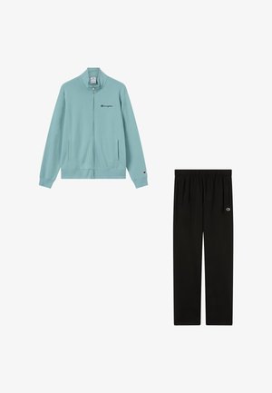 Jasnoniebieska kurtka Champion na zamek błyskawiczny oraz czarne spodnie dresowe Champion, oba z małymi naszywkami z logo na rękawach i nogawkach.