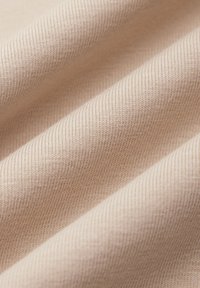 Jasno beżowy materiał o gładkiej, prążkowanej teksturze. Tkanina wydaje się być miękka i jest wyeksponowana w delikatnych fałdach.