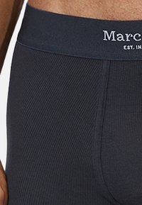 Dunkelgraue gerippte Unterwäsche mit einem festen Bund, der die "Marc"-Markierung zeigt. Das Material scheint weich und die Passform ist figurbetont.