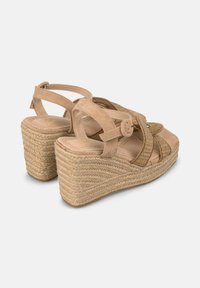 Beige wedge sandalen met een gestructureerde suede bovenkant, kruislings strapjes en een geweven jute hak. Voorzien van een gesp voor een verstelbare sluiting.